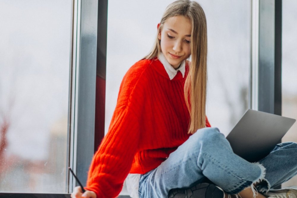 Elevă care studiază pentru Bac la psihologie cu ajutorul unui laptop