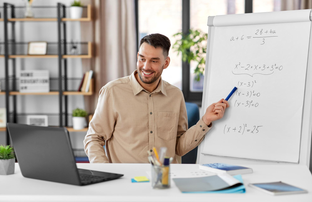 Profesor de matematică explicând exerciții și ecuații pe o tablă, în timpul unei lecții online